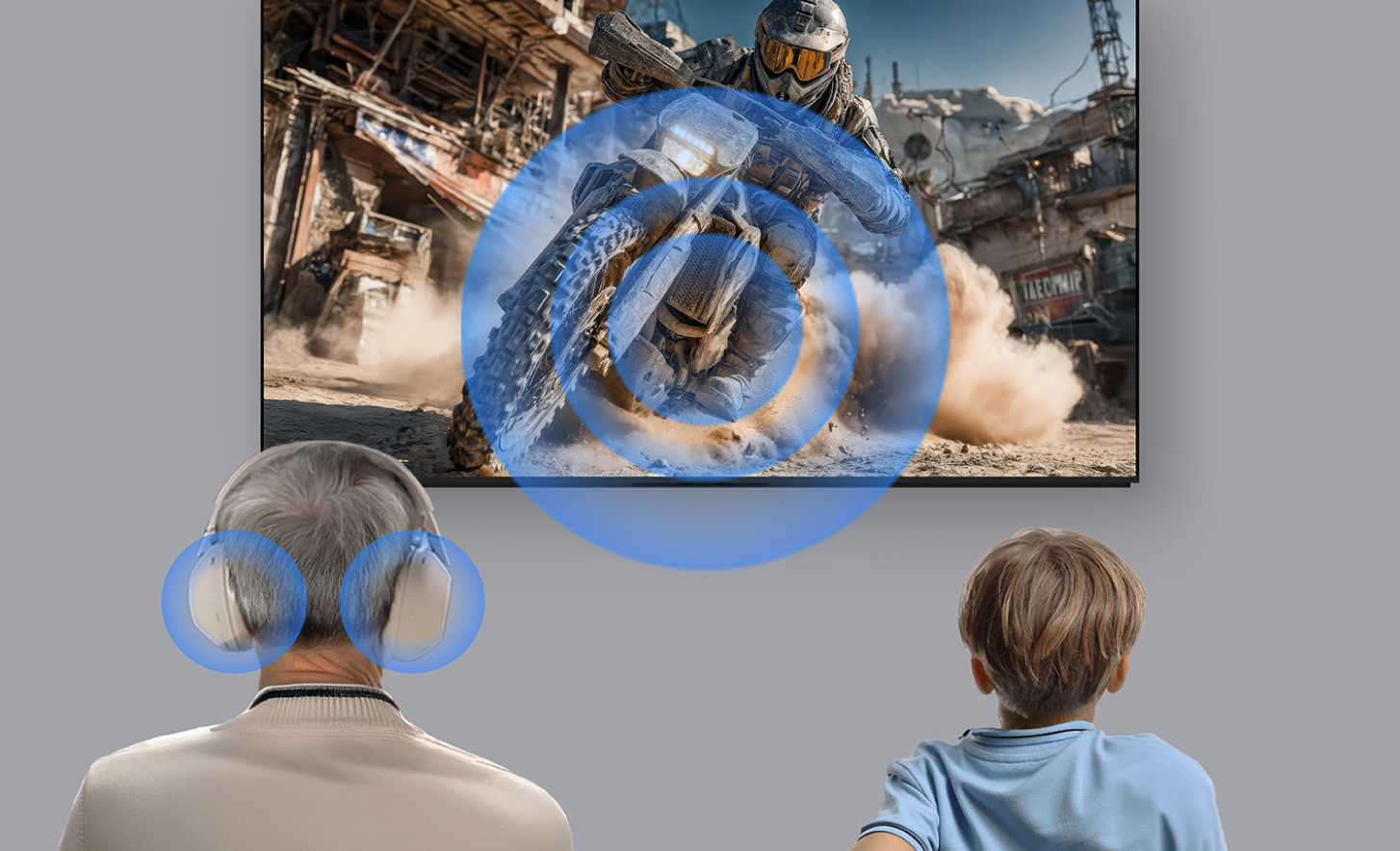 Un adulto mayor con audífonos puestos y un niño sentado a su lado ven una escena de acción en la pantalla una televisión. Las ondas de sonido azules irradian desde la pantalla hacia el oyente, lo que ilustra la reproducción de audio compartida o simultánea, de modo que ambos espectadores experimentan el mismo sonido del contenido.